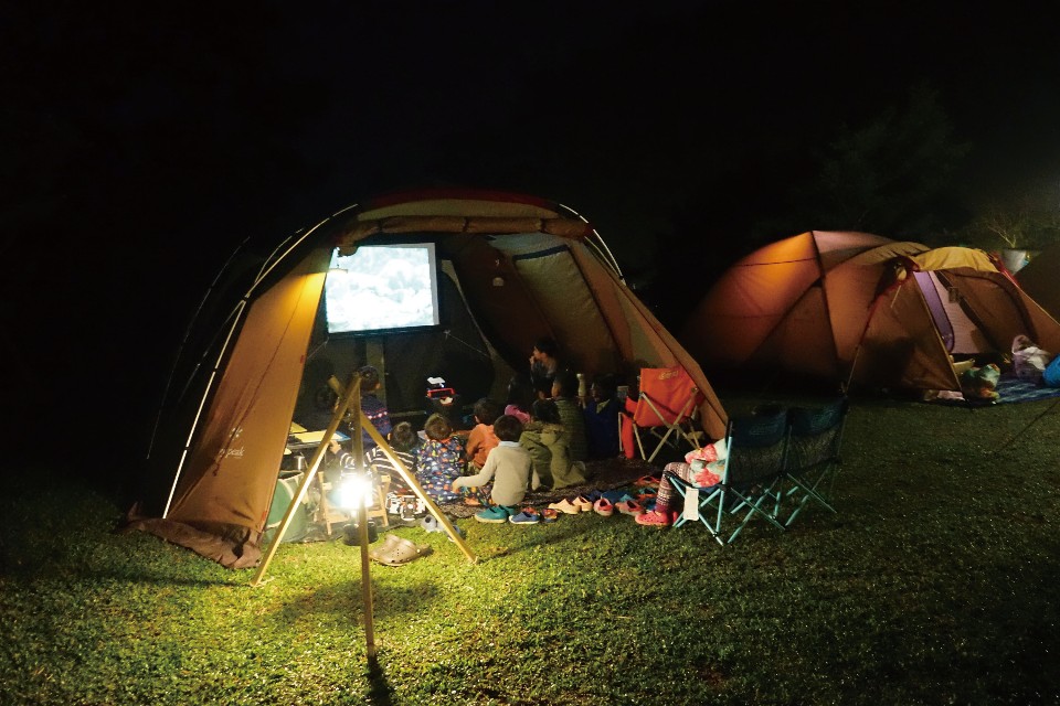 一家人窩在帳篷中，享受溫馨的電影時光。（圖片來源／《劉太太和你露營趣》）