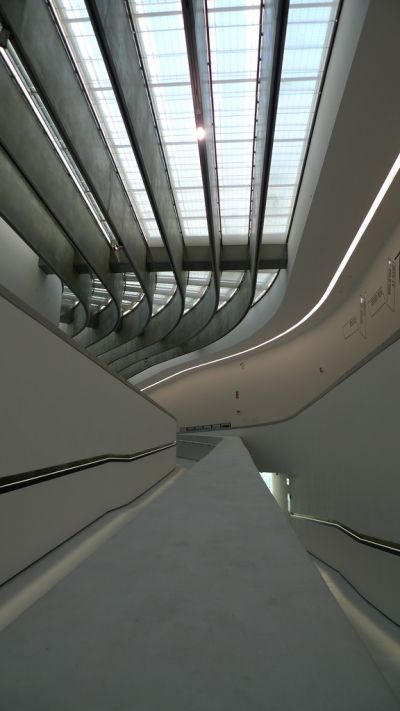 不同樓層的展覽空間，也透過坡道來銜接引導；上方的採光隔柵一方面做為光線的導版，另一方面也強化空間流動的軸向。(攝影/林芳怡)