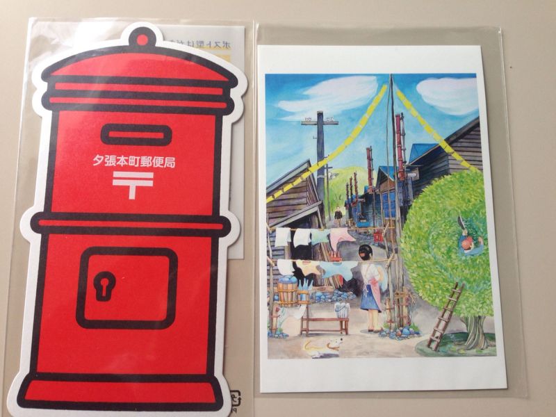 畫家以黃色手帕一片為題為夕張畫了一系列的圖（右）；夕張郵局的造型明信片（左）蠻可愛的，但郵資220?比一般方形明信片70?貴蠻多。(陳逸 攝)